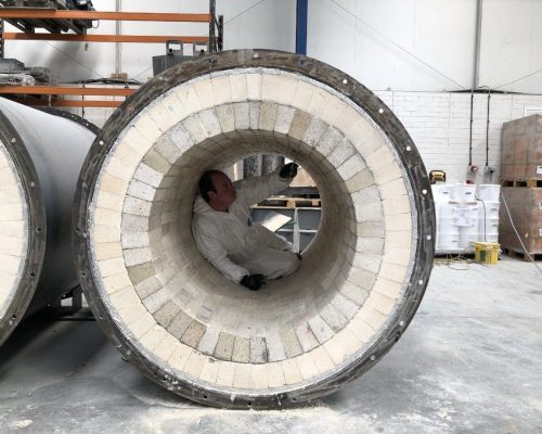 Man laying a refractory brick chamber inside a very large chamber